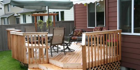 A wooden deck with an umbrella and chairs.