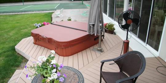 A hot tub on a deck with a fan.