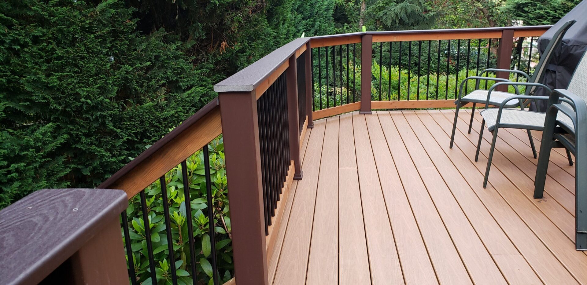Large composite deck on colonial style house With Brown Color Railing.