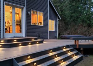 A deck with lighting and steps leading to a house.