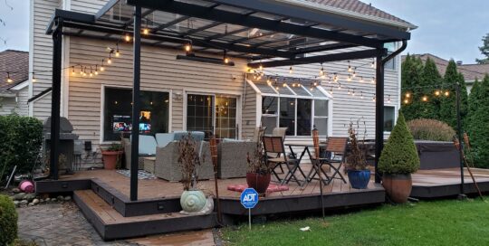 A backyard with a covered patio and string lights.