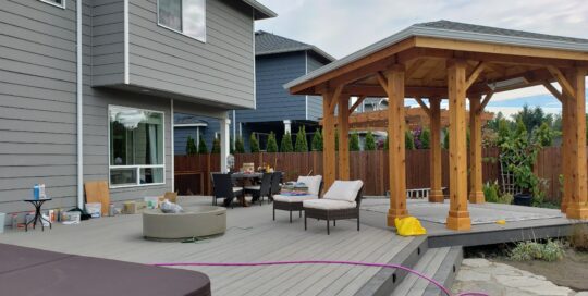 A cozy, covered backyard deck with composite decking, couch